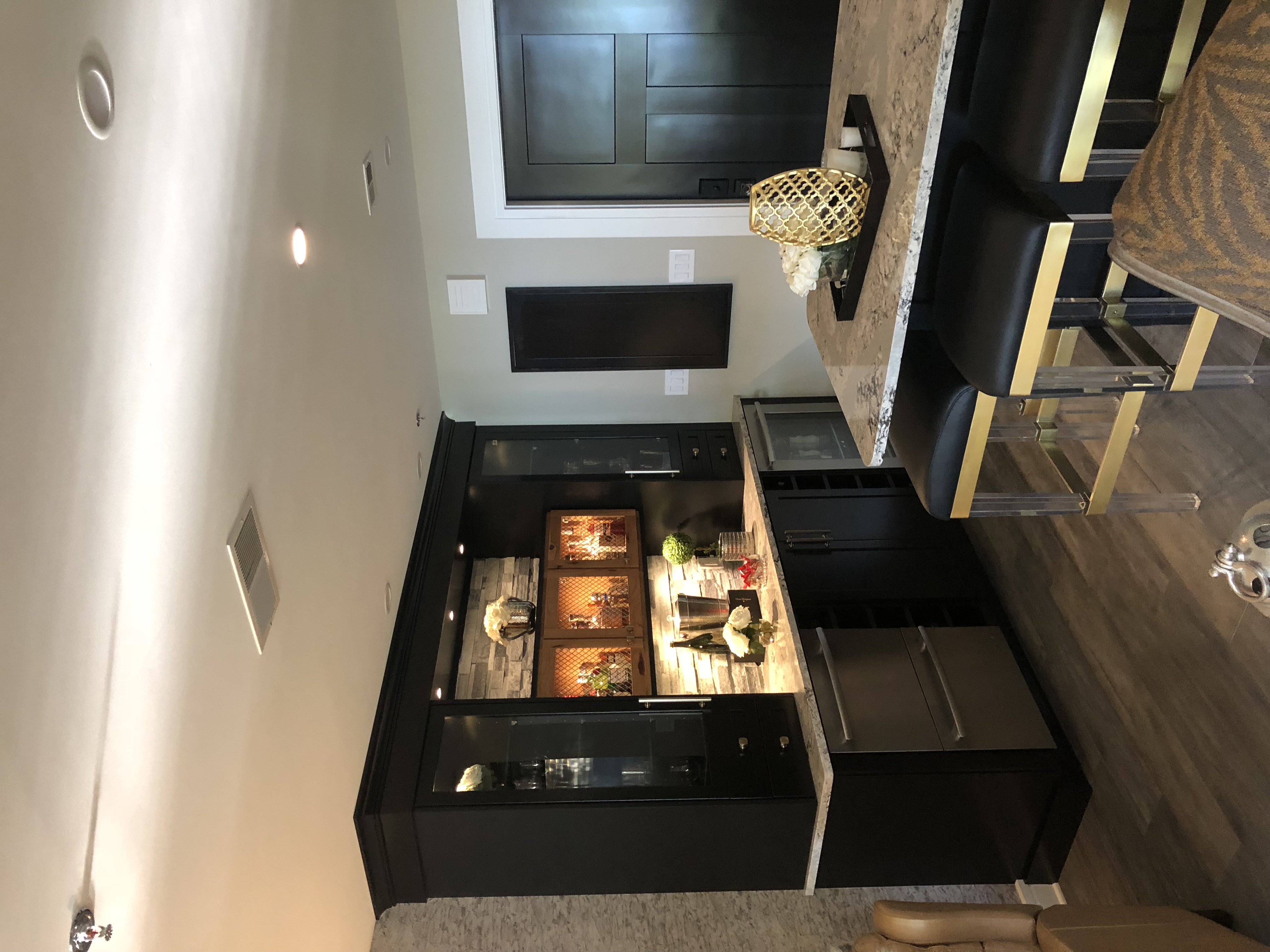 A counter-top bar, with glassware in cabinets on either side and stainless steel appliances with wine and storage underneath