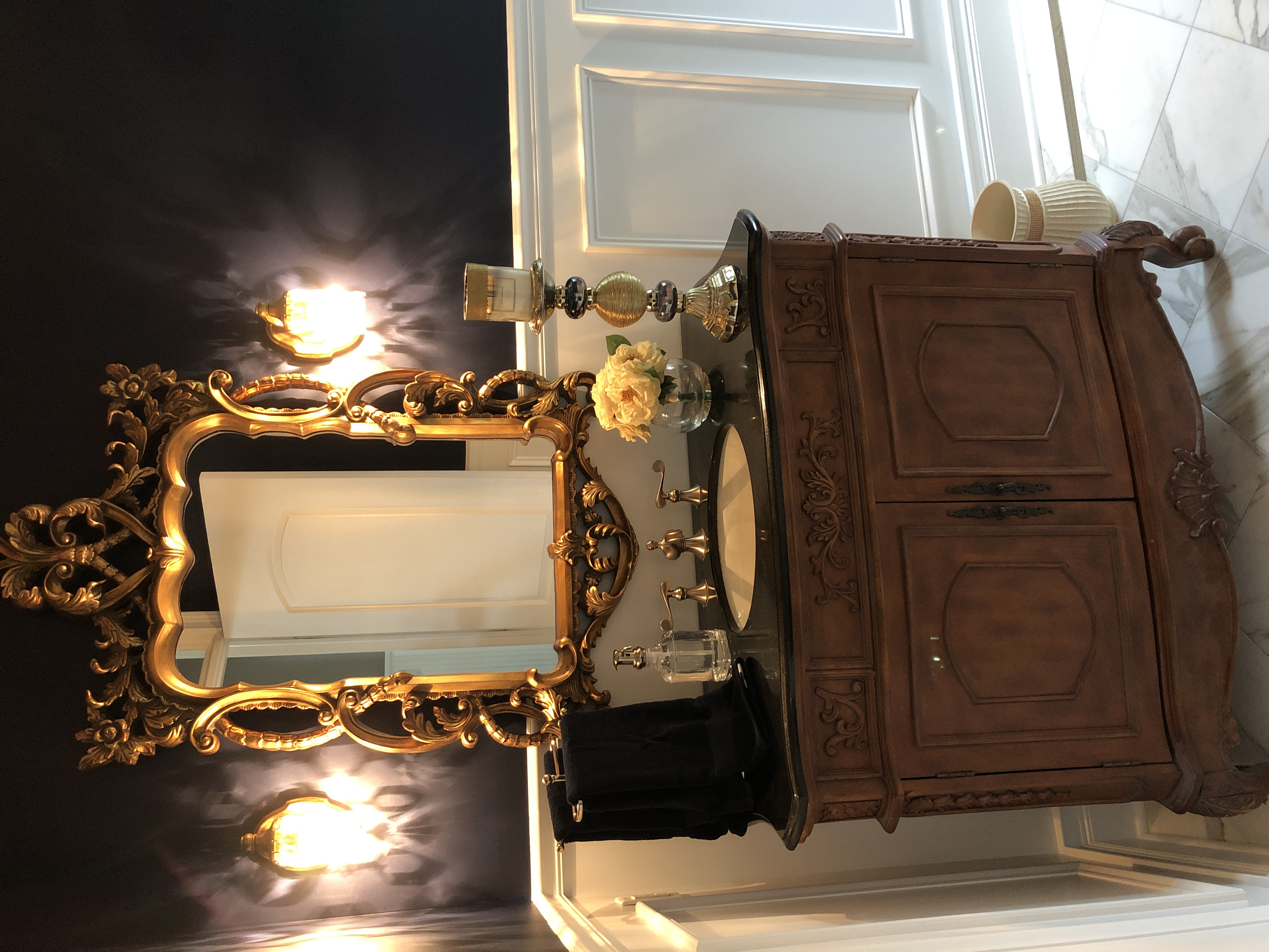 A single sink vanity with a large golden ornate mirror above