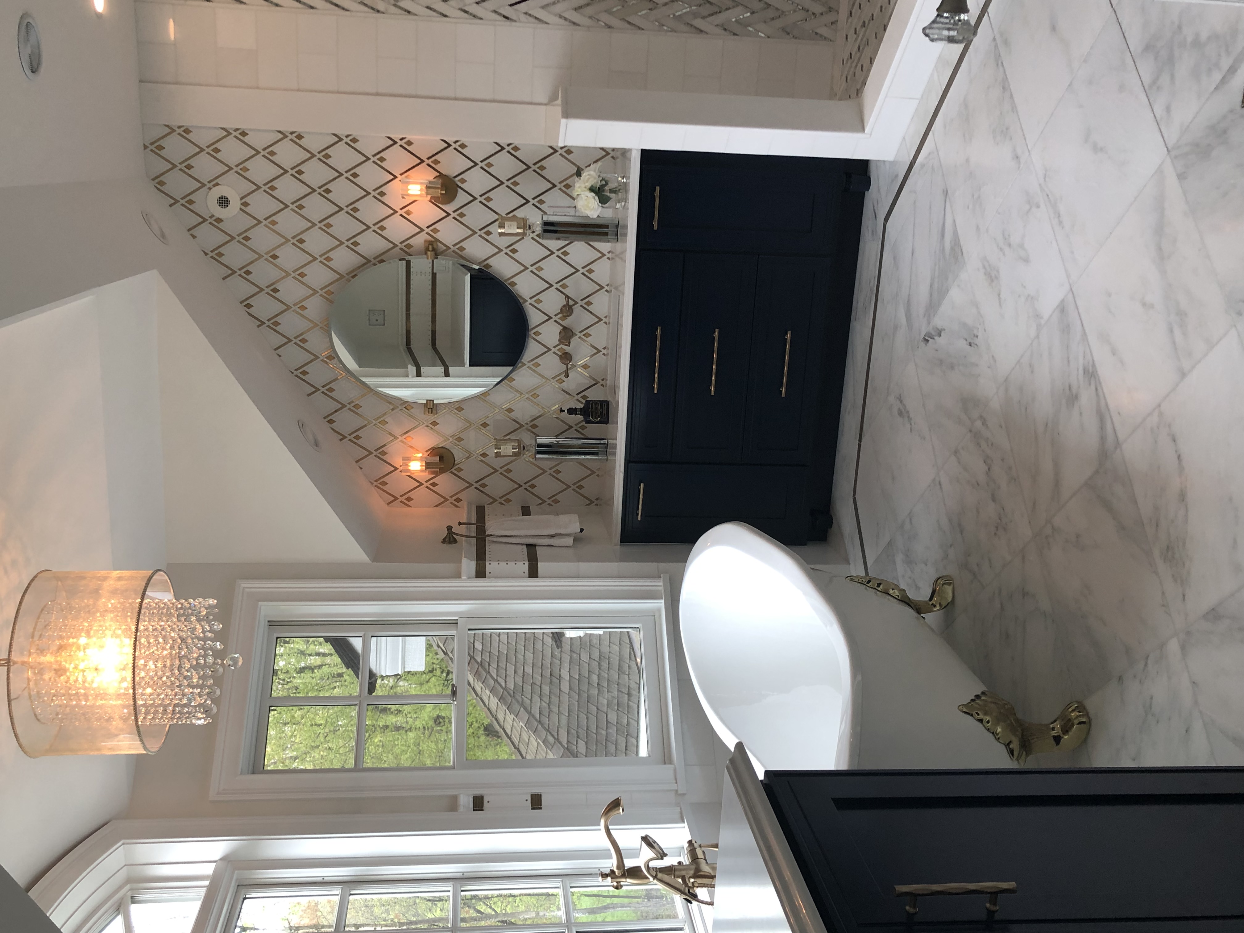 A view of the bathroom vanity with a claw-foot tub next to the window