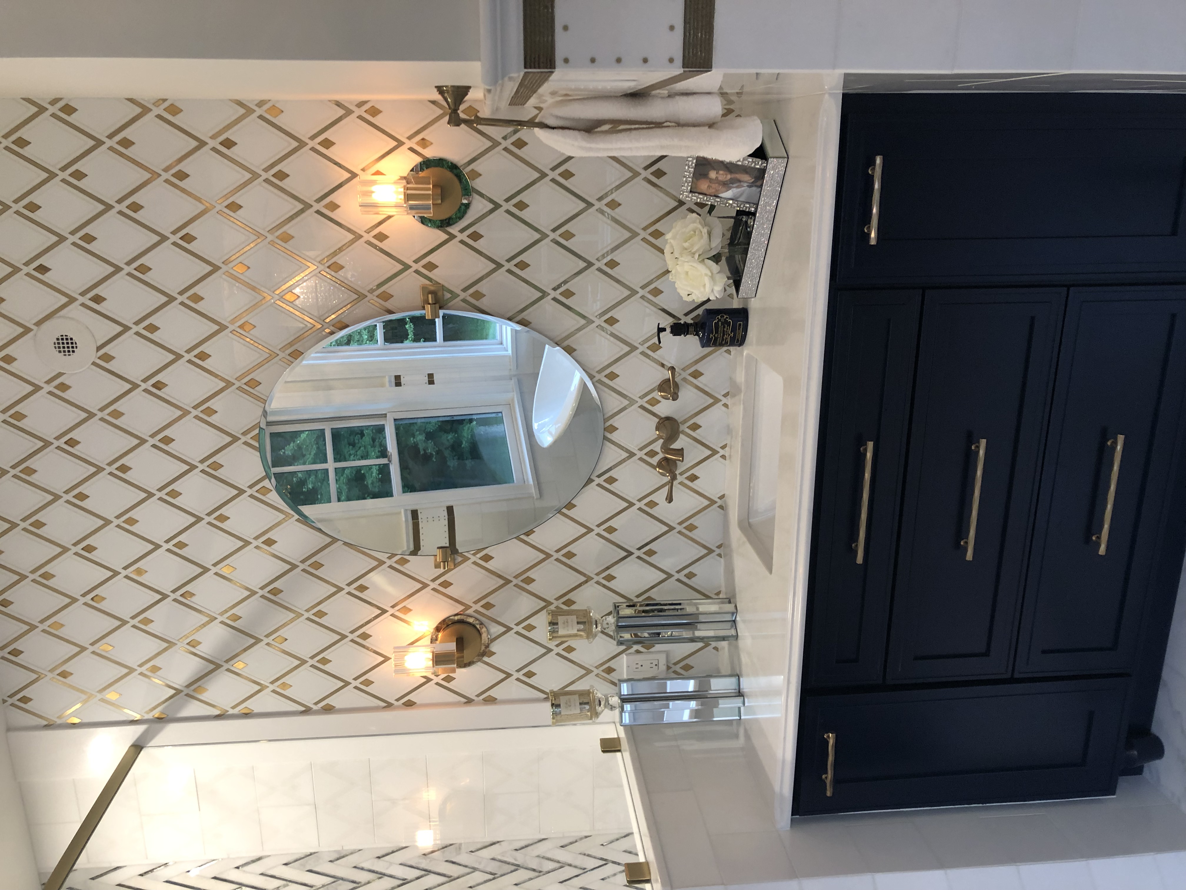 A single sink vanity with a golden diamond shaped pattern above it